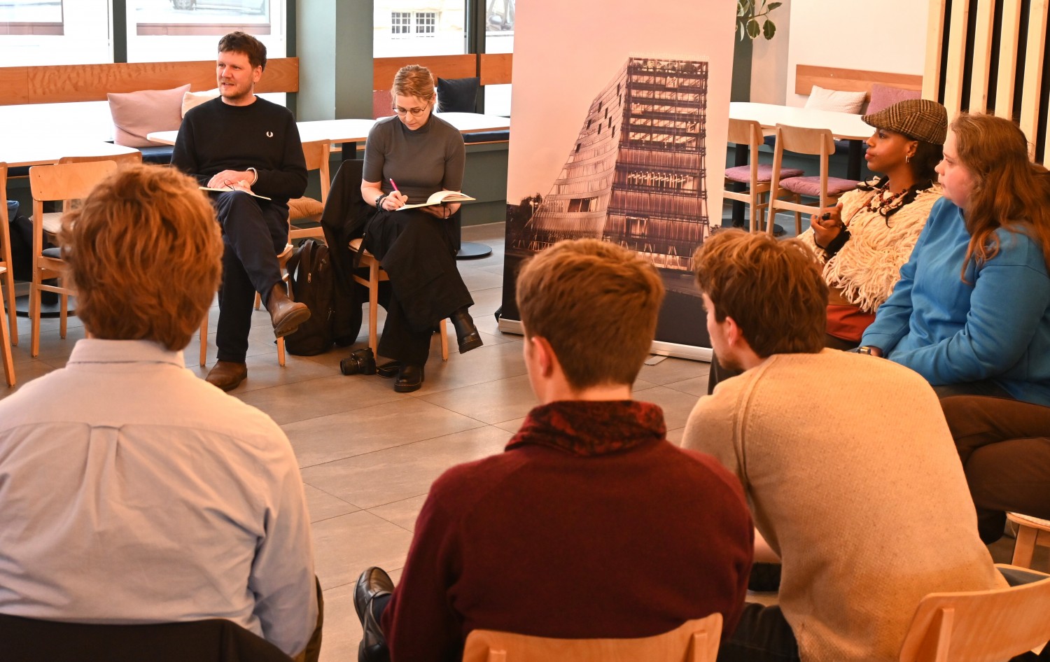 Studenten in gesprek met Kevin Breß en Lotte Caudri van het Zukunftszentrum in Halle. Ontwerp van het gebouw op de poster. Lynn Stroo/Duitslandweb