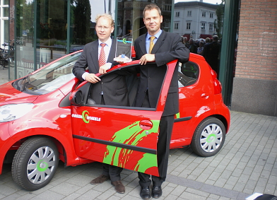Van Lookeren Campagne en Borghuis met hun prijs bij een Greenwheels-auto. Afbeelding: DIA